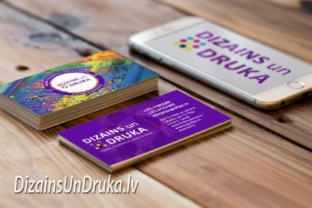 Uz koka galda izvietotas Dizains un Druka vizītkartes un viedtālrunis