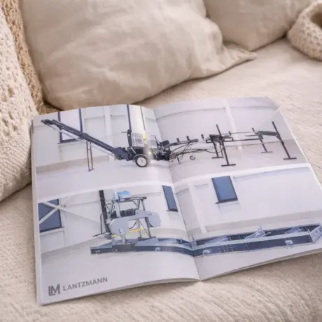 Uz dīvāna atvērta Lantzmann brošūra, demonstrējot kvalitatīvu druku