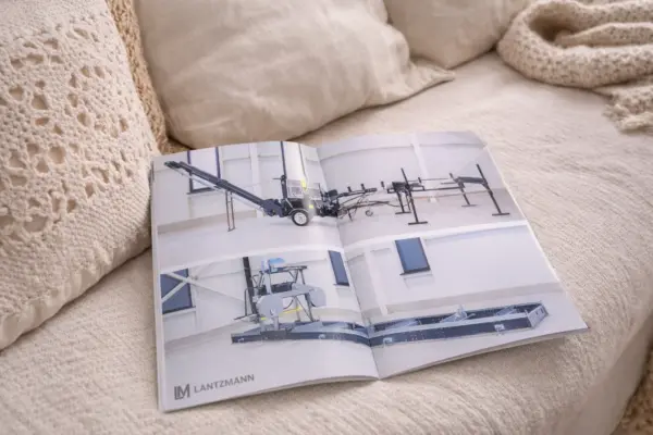 Uz dīvāna atvērta Lantzmann brošūra, demonstrējot kvalitatīvu druku