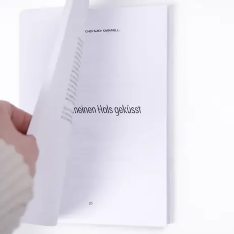 Рука перелистывает страницу в качественно напечатанной книге в мягкой обложке