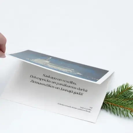 Roka atver Ziemassvētku apsveikuma kartīti ar individuālu dizainu un egles zaru