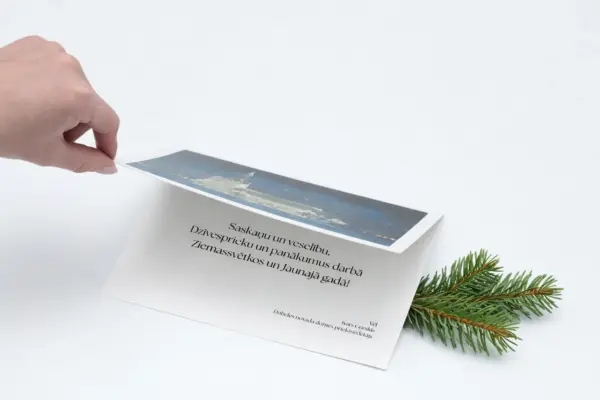 Roka atver Ziemassvētku apsveikuma kartīti ar individuālu dizainu un egles zaru