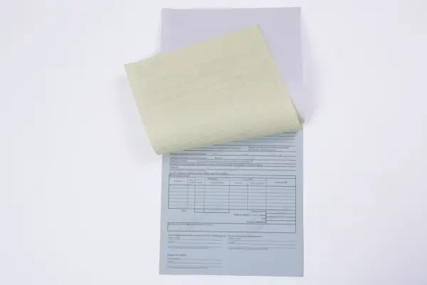 Paškopējošo veidlapu komplekts ar paceltu dzelteno lapu un pelēku kopiju