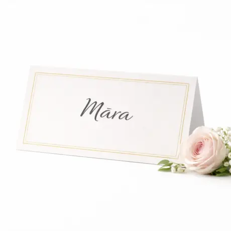 Настольная карточка с золотой рамкой и именем Māra рядом с розой