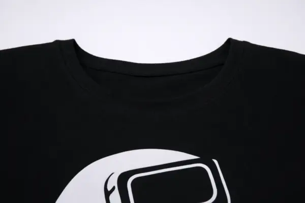 Melns T-krekls ar apdruku tuvplānā, redzams apaļš kakla izgriezums