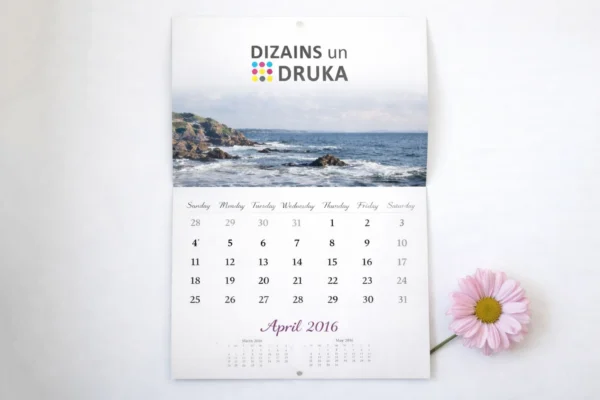 Перекидной настенный календарь с морским пейзажем и месяцем апрель рядом с розовым цветком