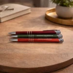 Three engraved metal pens on a wooden surface