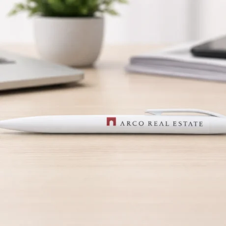 White custom plastic pen with printed logo on a desk