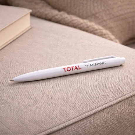 White custom plastic pen with TOTAL TRANSPORT print on a beige fabric surface