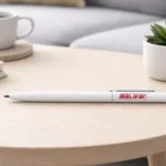 Balta plastmasas pildspalva ar apdruku BOLIVAR uz gaiša galda