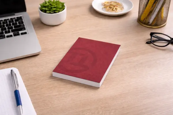 Sarkans firmas bloknots ar logotipu uz koka biroja galda