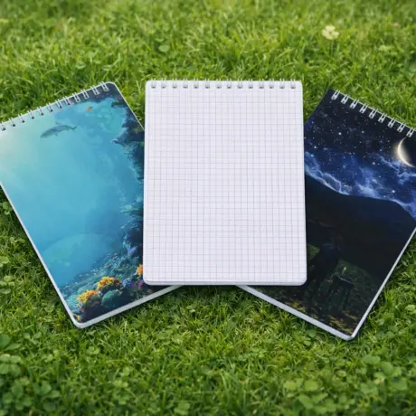 Trīs spirāles bloknoti ar individuālu dizainu un rūtiņu lapām zālē