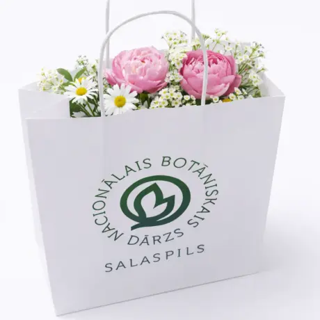Balts papīra maisiņš ar apdruku Nacionālais botāniskais dārzs, pildīts ar ziediem