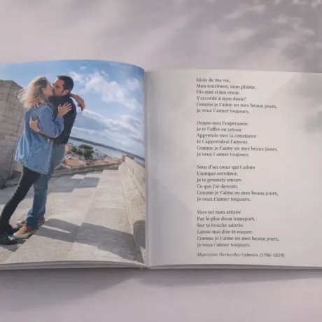 Atvērta fotogrāmata ar pāra ceļojuma fotogrāfiju un dzejas rindām