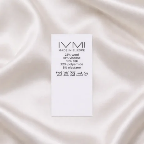 Balta neilona birka apģērbiem ar drukātu sastāvu un kopšanas instrukciju