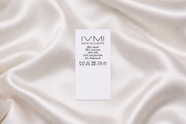 Balta neilona birka apģērbiem ar drukātu sastāvu un kopšanas instrukciju