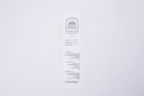 Balta neilona birka ar druku, Pils Matrači logo un kopšanas instrukciju