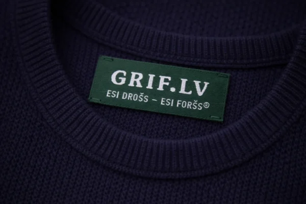 Green custom woven jacquard label with GRIF.LV on a dark blue sweater collar